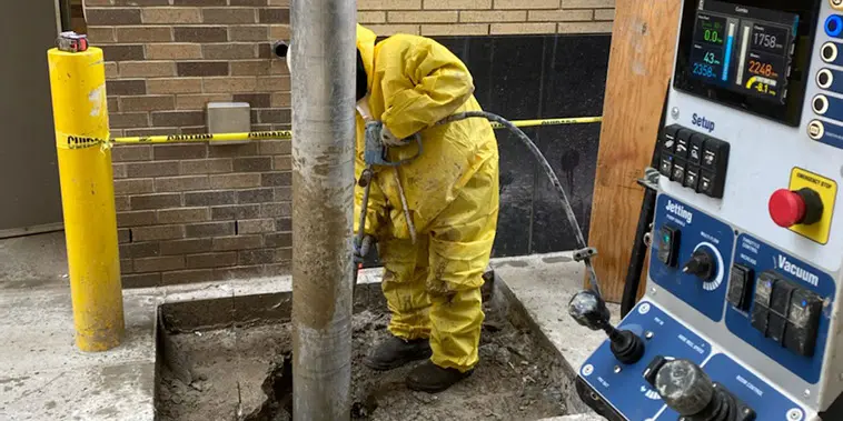 A man in yellow suit working on pipe.